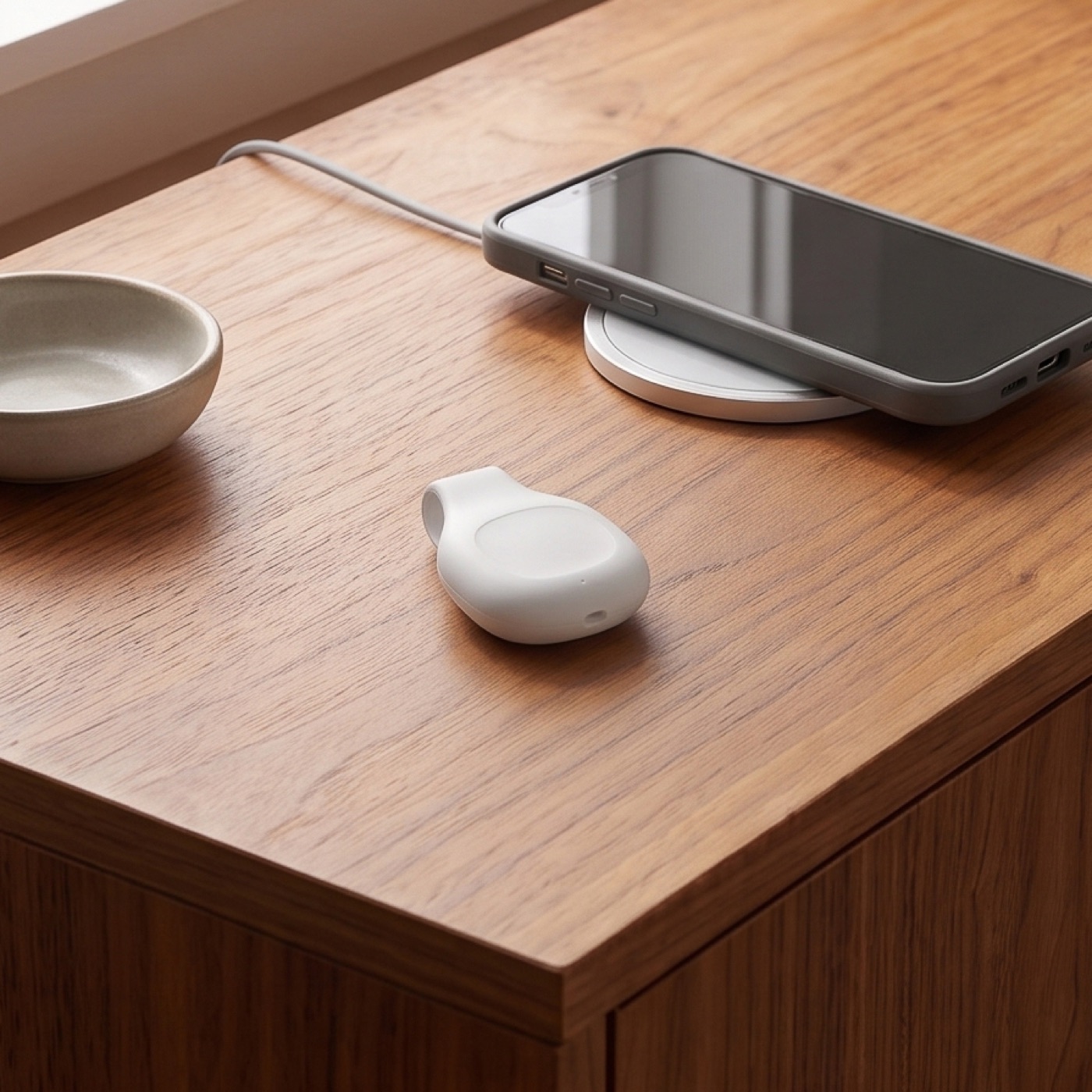 The Halo device resting on a walnut cabinet beside a phone on a charging pad.